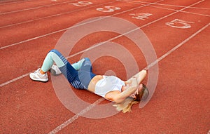 Tired woman runner taking a rest after run lying on the running