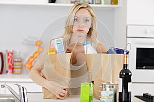 tired woman sighing as she puts down shopping bags