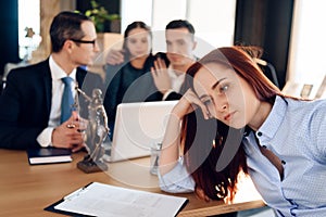 Tired woman sits and puts her hand on lawyer table