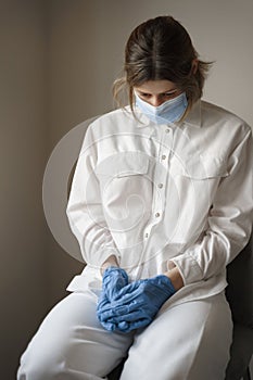 Tired woman sitting in protective medical face mask. Protection from Coronavirus, covid-19. Medical worker