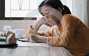 Tired woman sitting writing book on table in office. working from home concept.