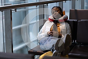 Tired woman sleep in airport on chair with legs on suitcase waiting for transit flight departure