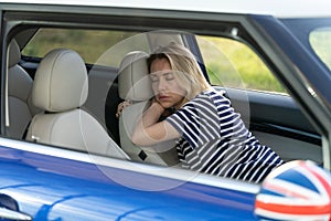 Tired woman sleep inside car on driver seat. Unhappy adult female fall asleep on parking after work