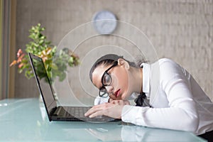 Tired woman sleeping on desk at laptop