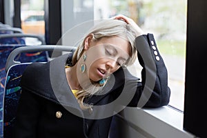 Tired woman sleeping while riding to work in public transport