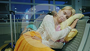 The tired woman sleeps in the terminal of the airport. Cancellation or delay of the flight concept