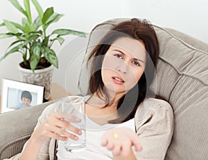 Tired woman taking her medicine lying on the sofa