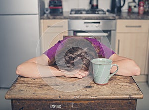 Tired woman with tea in kitchen