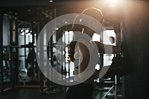 Tired woman wearing boxing gloves leaning on a punching bag in the gym