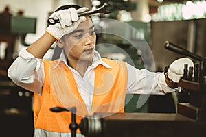 Tired woman worker Asian labor hard work in hot factory wiping away sweat working with metal machine