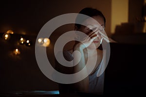 Tired woman working overtime on laptop computer at night