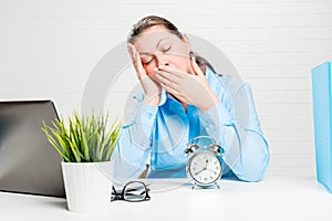 Tired woman yawns and wants to sleep at work