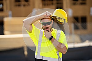 Tired worker. Worker man on the building construction. Construction site worker in helmet work outdoors. Builder workers