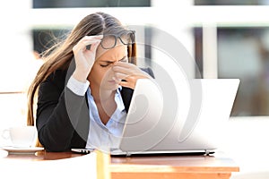 Tired worker suffering eyestrain in a coffee shop photo
