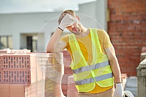 Tired worker touching face at construction site