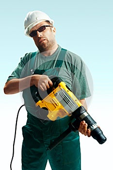 Tired workman in black glasses with perforator