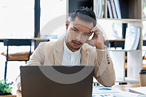 Tired and worried business man holding his head on hand at his workplace in the office