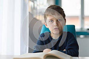 Tired 8 years old boy doing his homework at the table