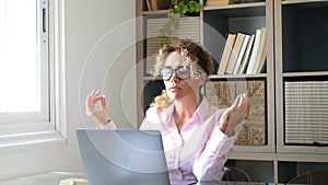 Tired young adult woman at work on laptop computer in home office try to calm and relax with meditation - concept of smart working