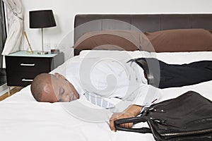 Tired young African American businessman sleeping in bed photo