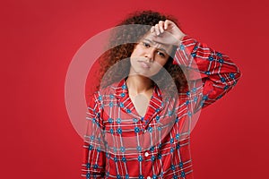 Tired young african american girl in pajamas homewear posing resting at home isolated on red wall background studio