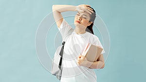 Tired young asian female student in casual clothes backpack hold books put hand on forehead have headache isolated on blue