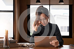 tired young asian woman office working with digital tablet at desk while trying to work. Exhausted businesswoman having