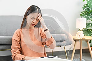 Tired young Asian woman sitting and have a headache because migraine. photo