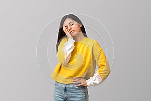 tired young attractive multi ethnicity woman in trendy yellow sweater against light grey background with palm on her
