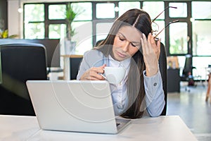 Tired young business woman with headache at office