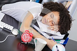 Tired young business woman sleeping on workplace