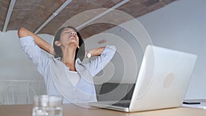 Tired young business woman taking a moment for relax while working with her laptop in the office.