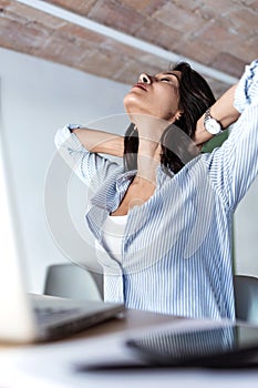 Tired young business woman taking a moment for relax while working with her laptop in the office