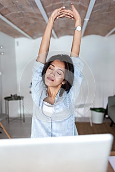 Tired young business woman taking a moment for relax while working with her laptop in the office