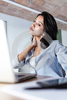 Tired young business woman taking a moment for relax while working with her laptop in the office