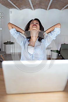 Tired young business woman taking a moment for relax while working with her laptop in the office