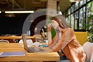 Tired young business woman working at coworking space