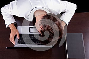 Tired young businessman with head on the computer