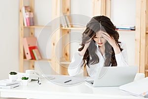 Tired young businesswoman suffering from long time sitting at computer desk in office