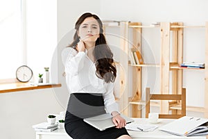 Tired young businesswoman suffering from long time sitting at computer desk in office