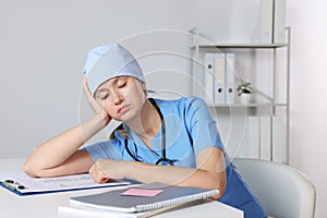 Tired young doctor sleeping at workplace in office