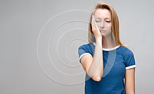 Tired Young female covers face her hand, feels fatigue, Weariness and people. Studio shot, gray background. Copy space