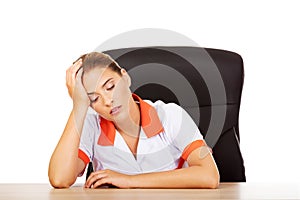 Tired young female doctoror nurse sitting behind the desk