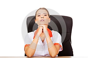 Tired young female doctoror nurse sitting behind the desk