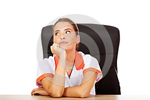 Tired young female doctoror nurse sitting behind the desk