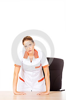 Tired young female doctoror nurse standing behind the desk