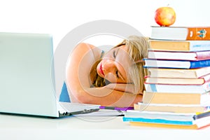 Tired young girl sleeping on table with laptop