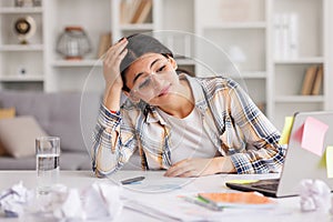 A tired young Indian girl gets angry from the number of tasks, crumples up the paper and throws it away, tries to calm