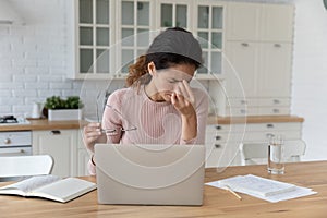 Tired young latin female distracted from laptop rub nose bridge