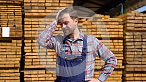 Tired young male worker in timber lumber warehouse